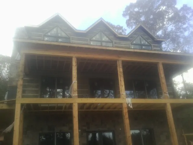 Dormers and porch framing on a large log home under construction — Roof Coating work by our crew in Central